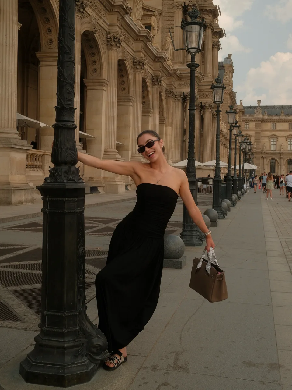 Diana in a black dress beside a lamppost near the Louvre
